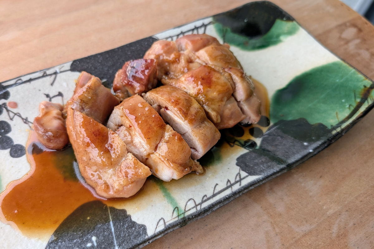 Sliced halal chicken teriyaki on a Japanese ceramic plate, rich glossy sauce, no mirin no sake